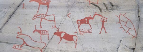 Røde helleristninger med dyr, mennesker og båter på berget